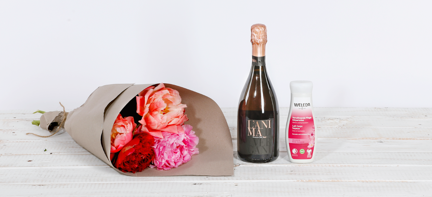 Peonies next to prosecco and a body lotion