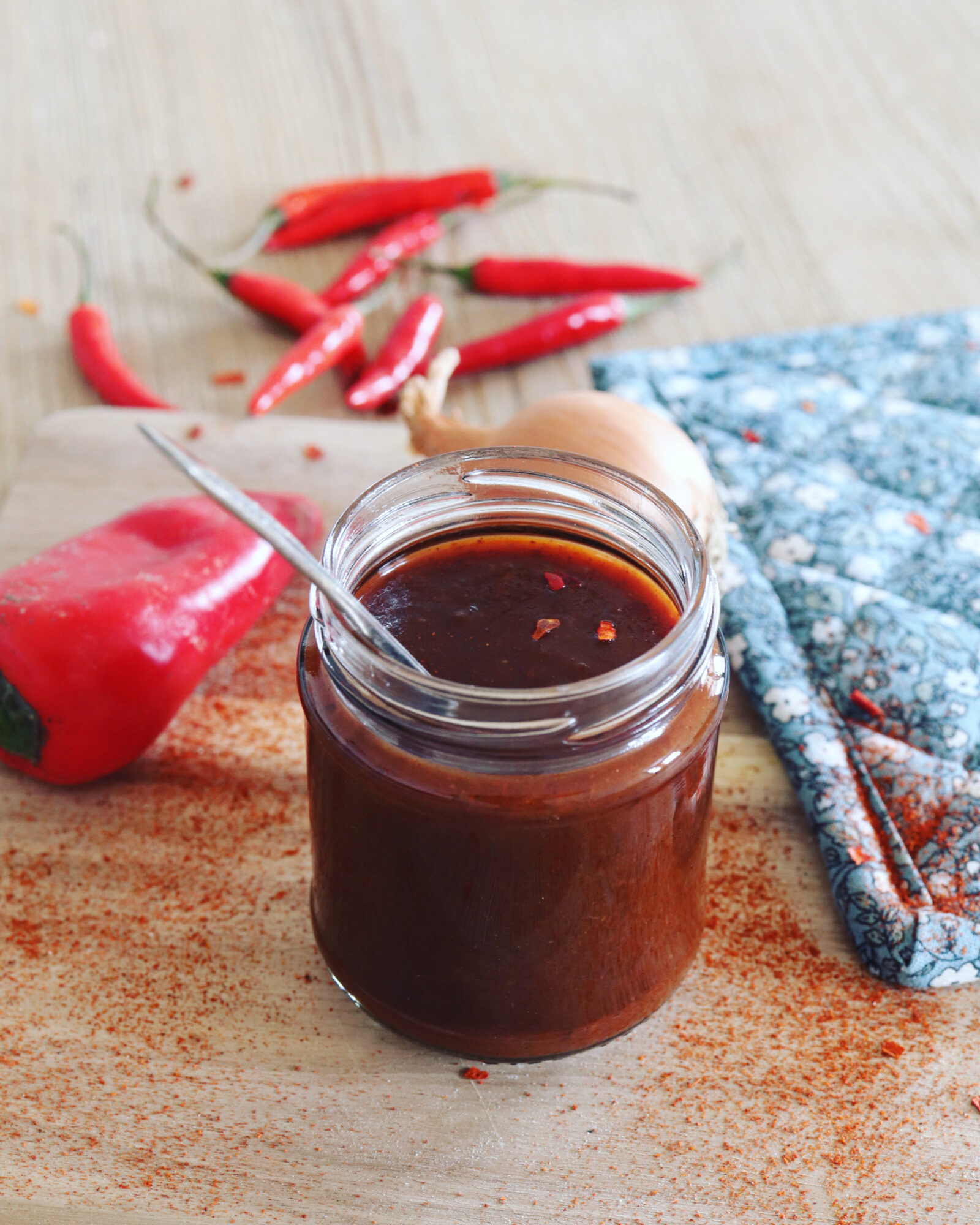 Barbecue sauce in a jar, red peppers in the background