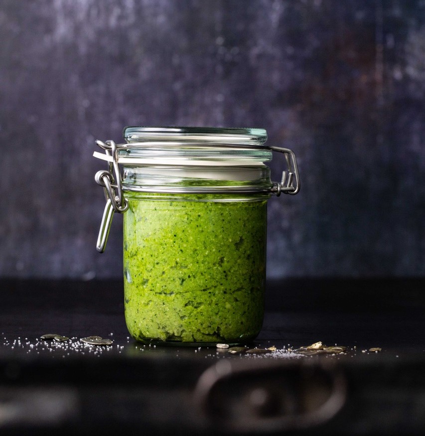 Green pesto in a mason jar, dark background